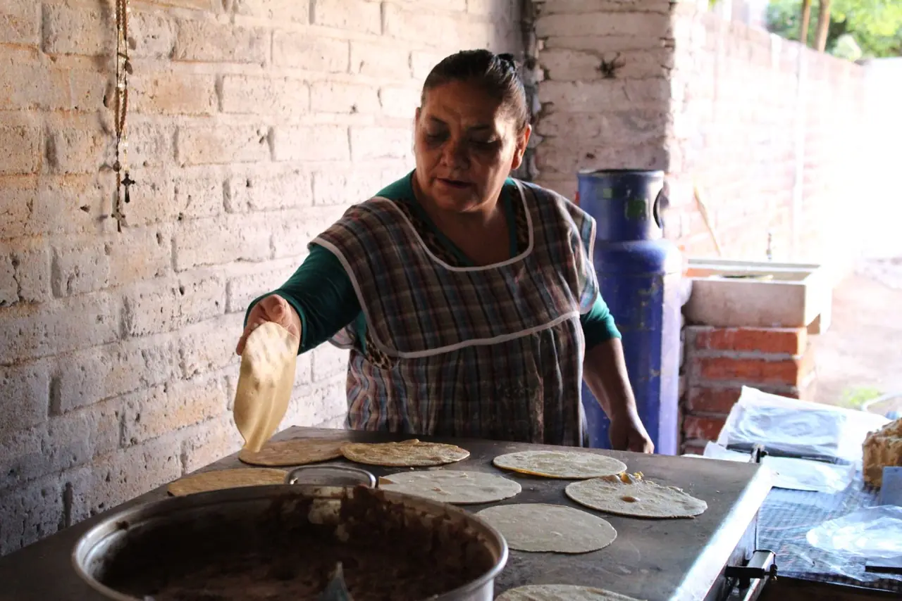 Cook preparing tortillas on a griddle
